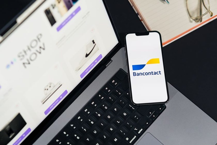Celular com aplicativo de pagamento aberto apoiado no teclado de um notebook exibindo uma loja virtual